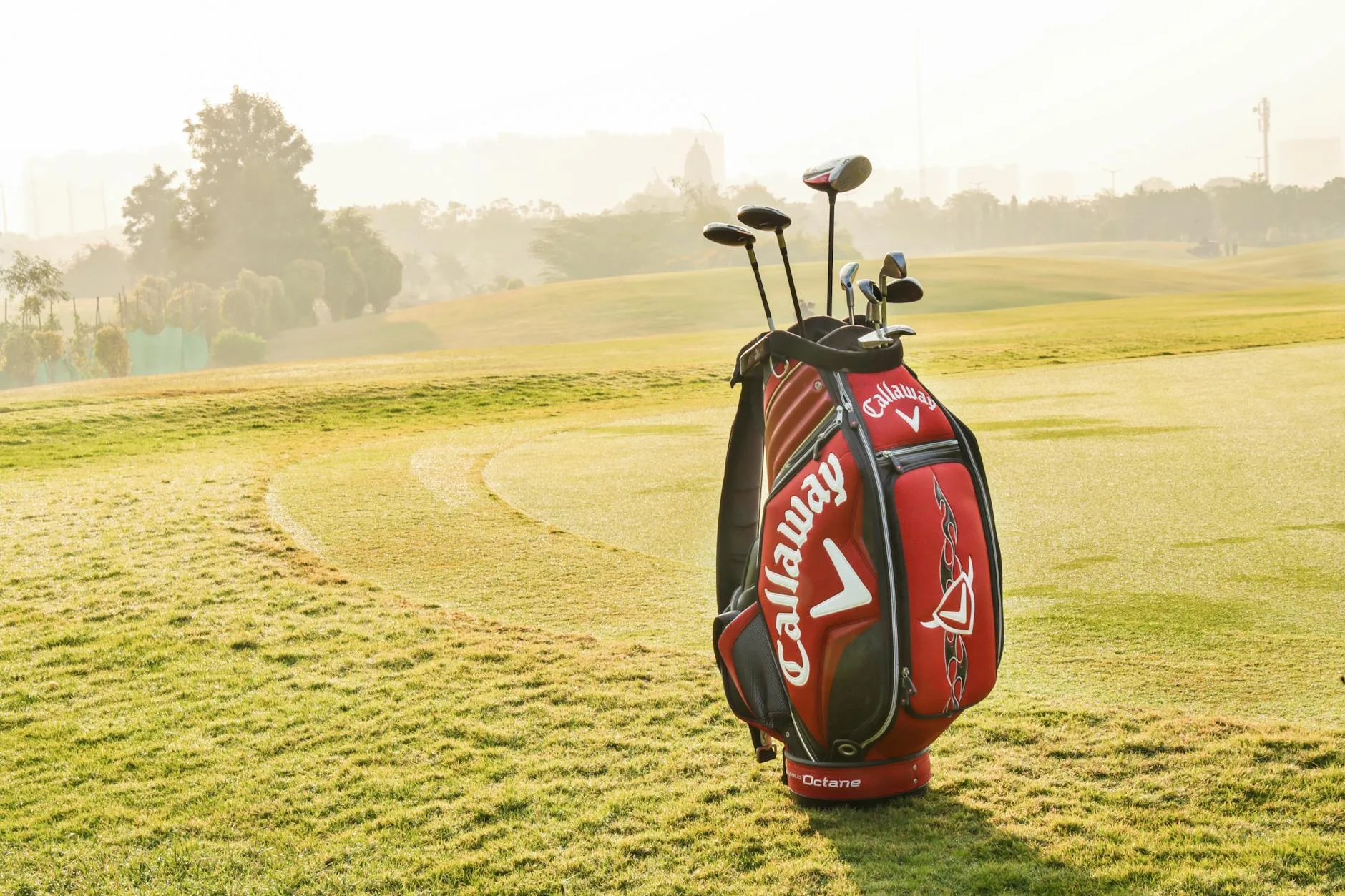 Golf clubs and equipment bag resting on grass at a golf course
