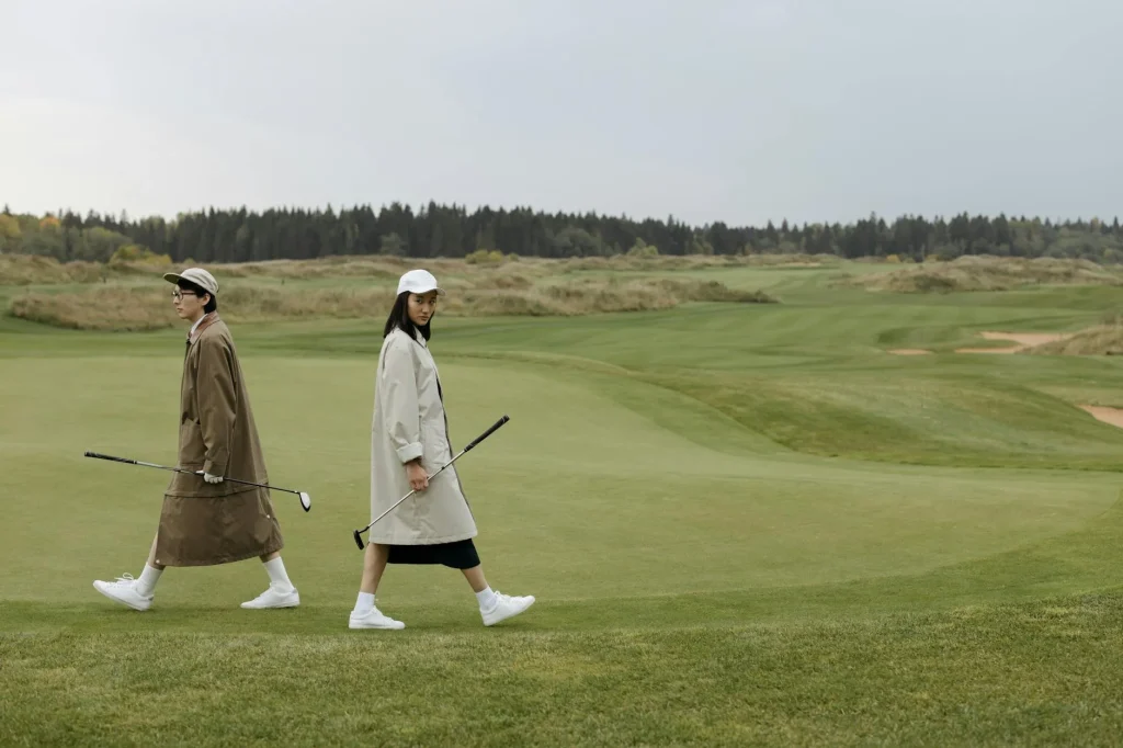 Golfers walking along a green golf course fairway