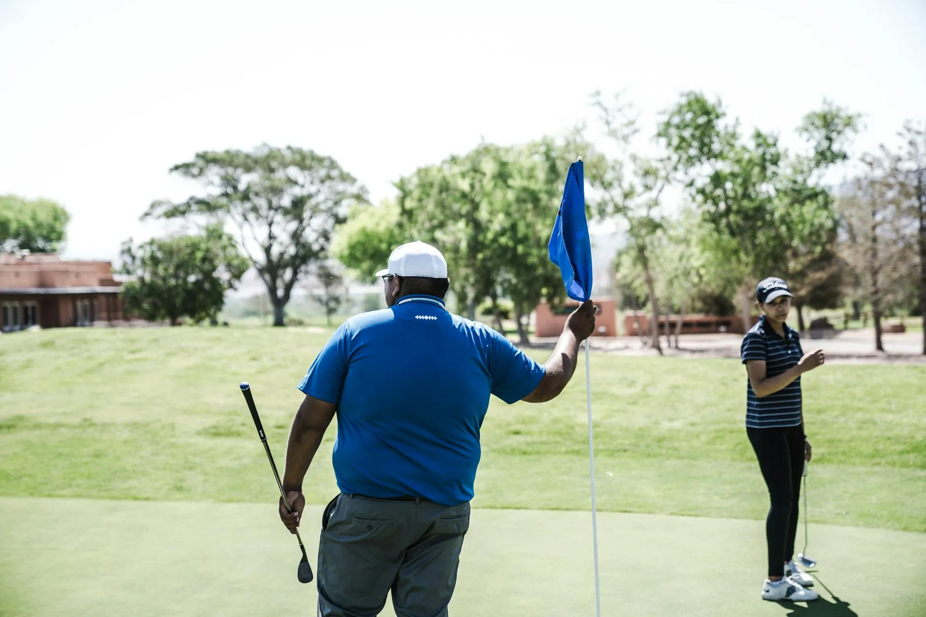 Golfer putting on green with flag pin in background