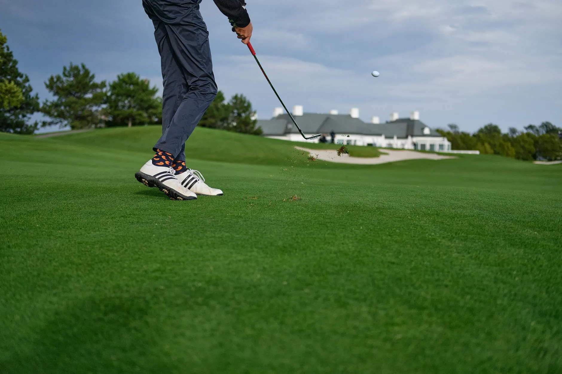 Close-up of a golf iron about to strike a ball on the fairway