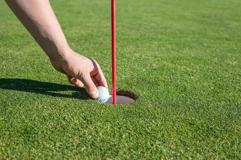 Golf ball rolling towards the hole on a putting green