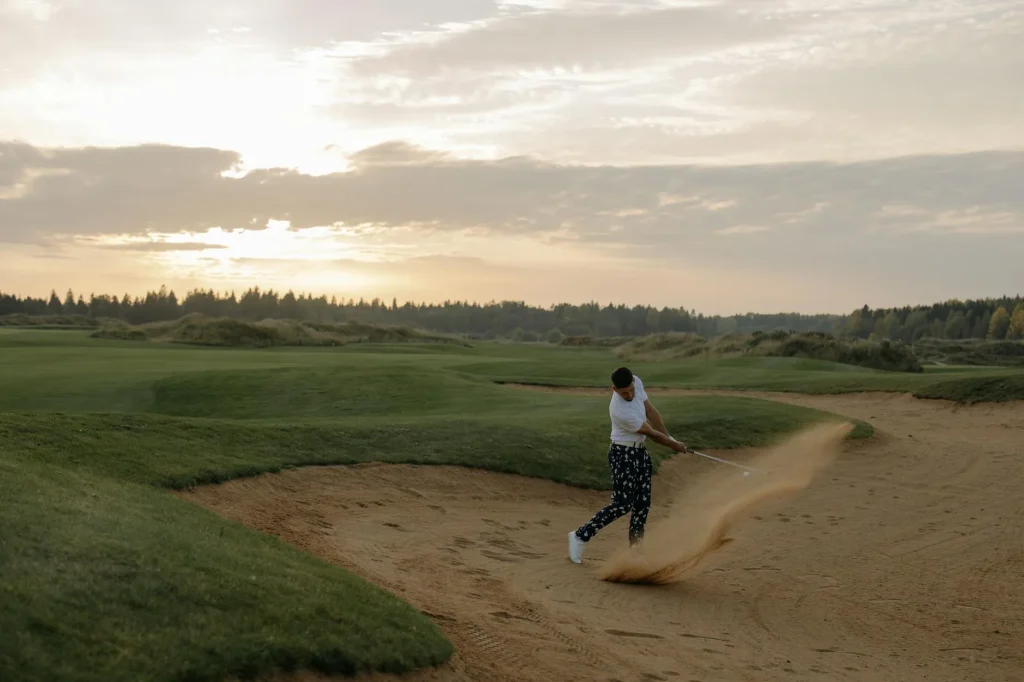 Close-up of a golf wedge club head in a sand bunker