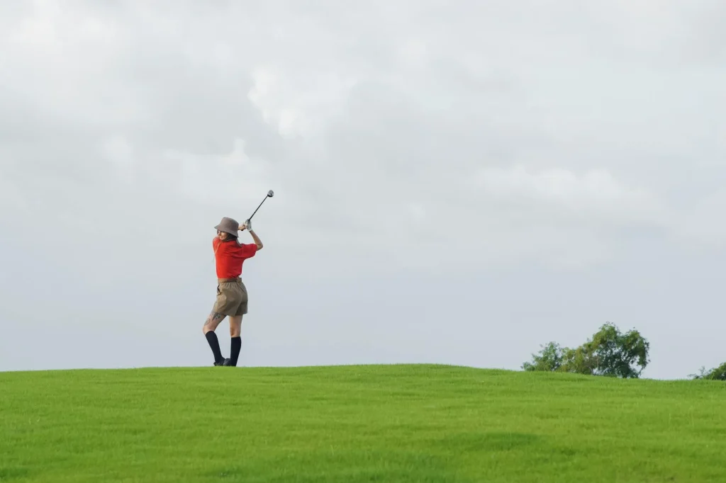 Golfer hitting a fairway shot with a hybrid club on course