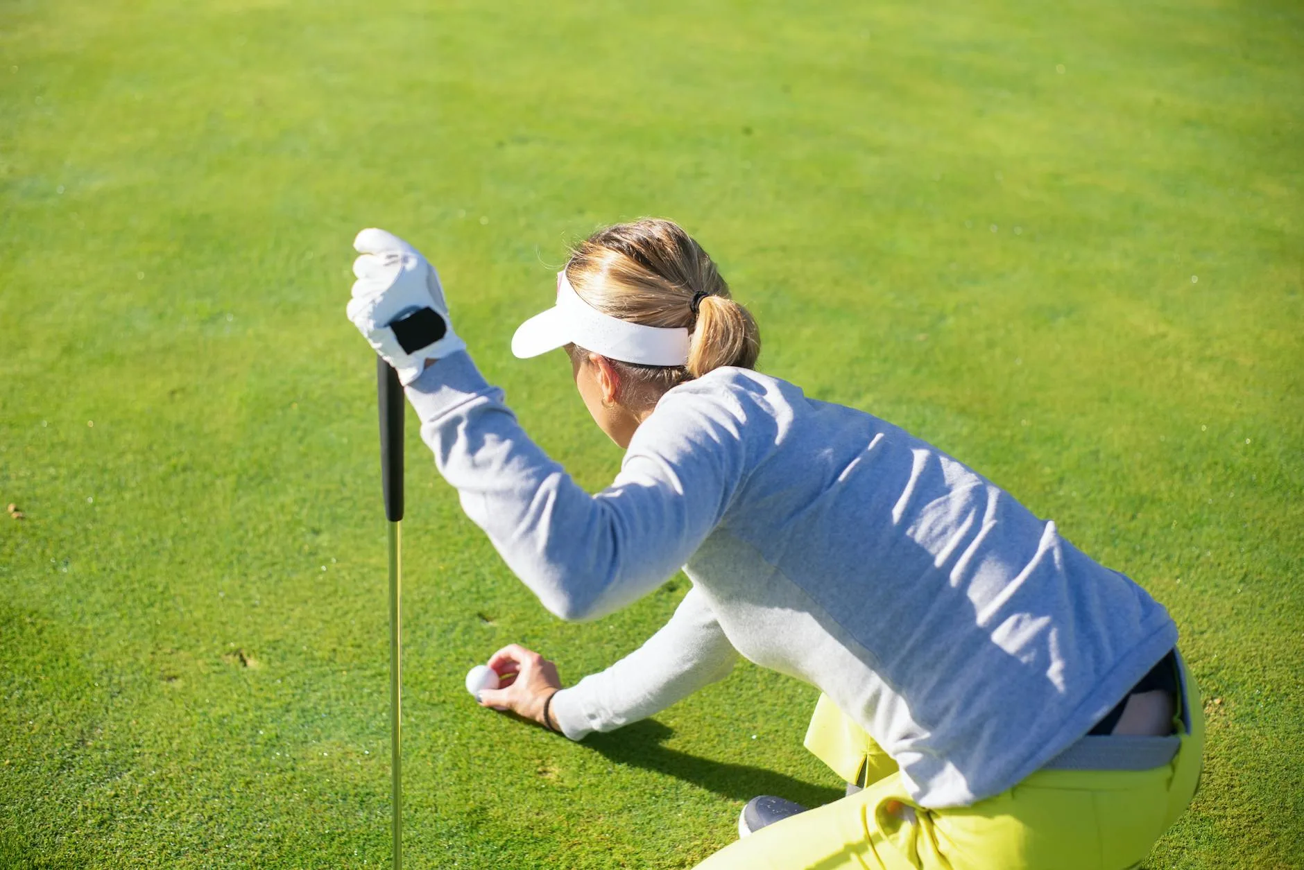 Golfer crouching to read the line on a putting green