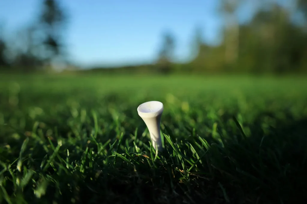 Golf ball on a tee on a green course in morning light