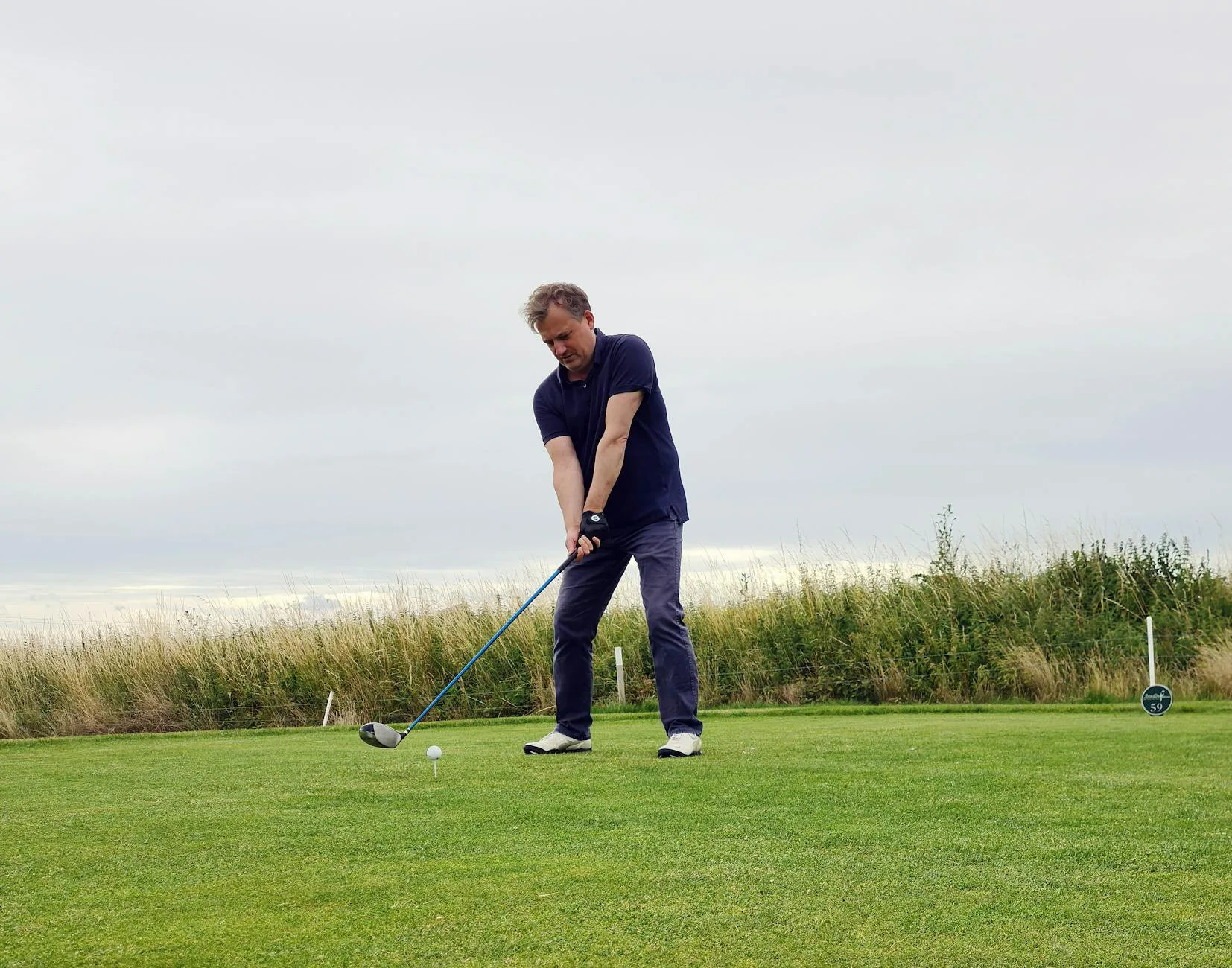 Golfer mid-swing at an outdoor driving range