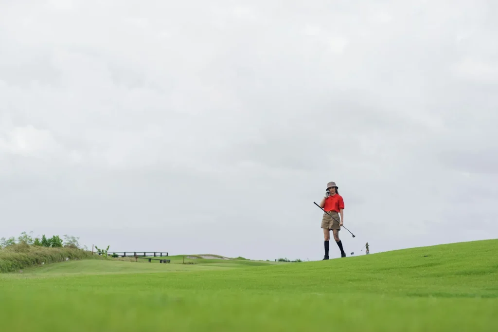 Golfer walking along a fairway on a green golf course