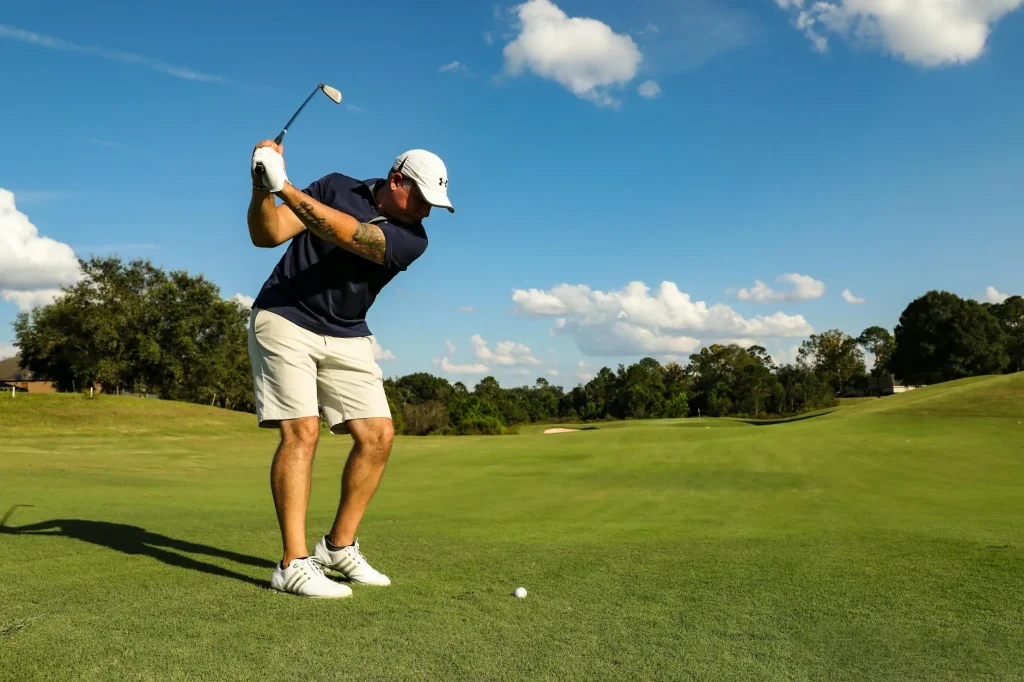 Golfer playing an iron shot on a green fairway