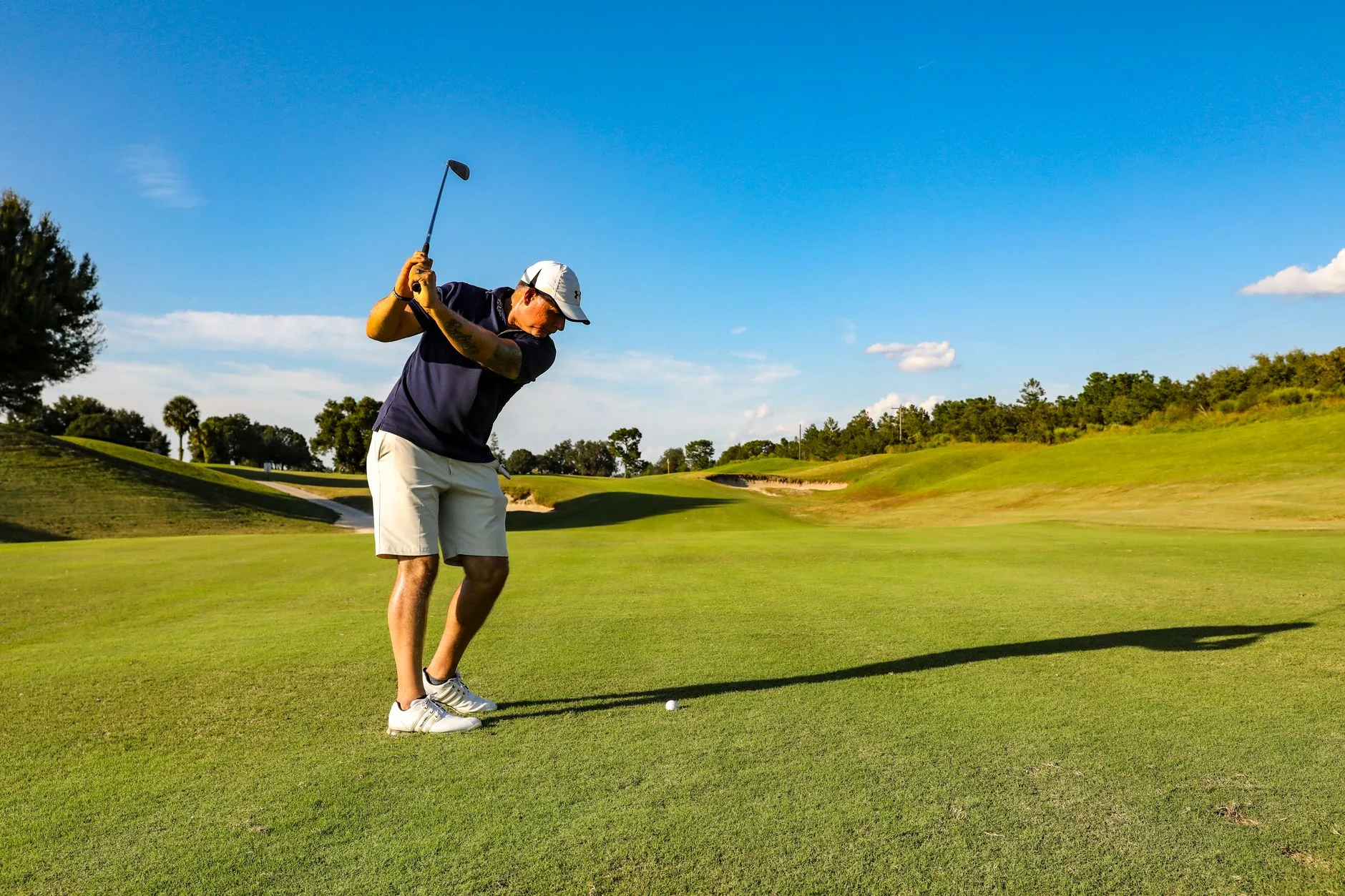Golfer wearing a cap and sunglasses on a sunny course