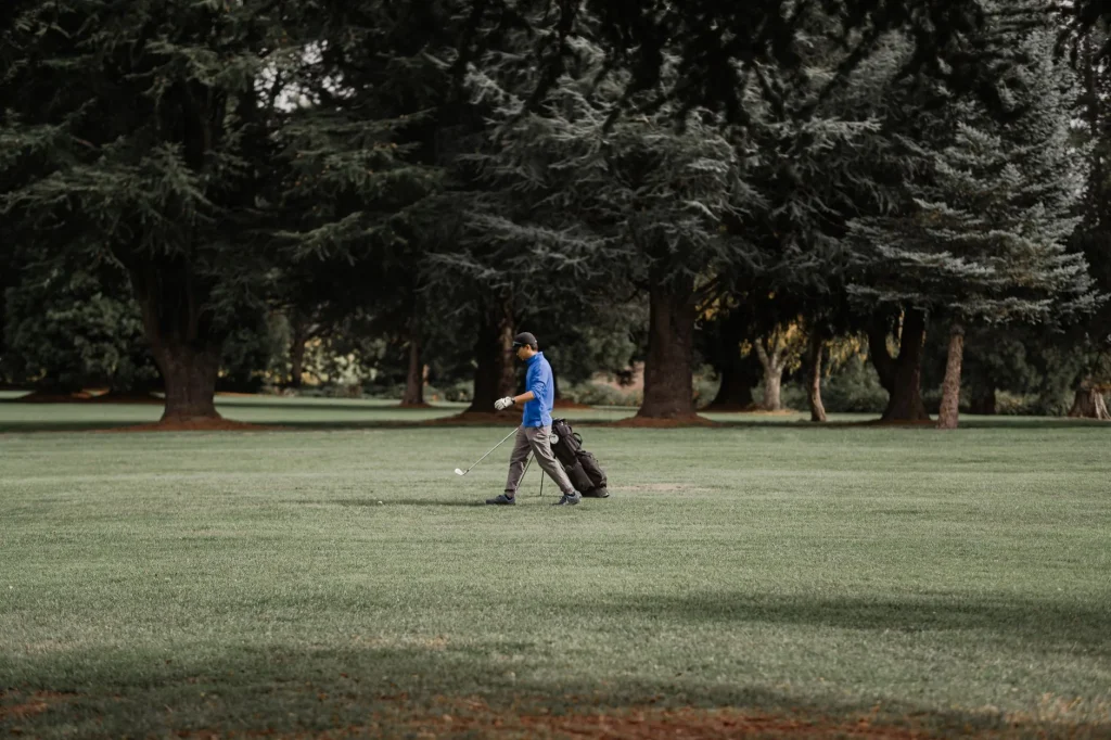 Golfer carrying a golf bag on the course with useful accessories